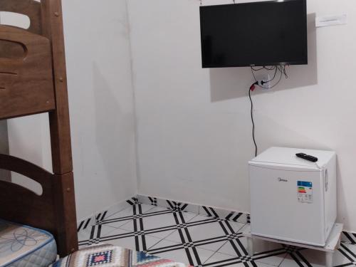 um quarto com uma televisão na parede e um frigorífico em Pousada Vicenzi em Luziânia