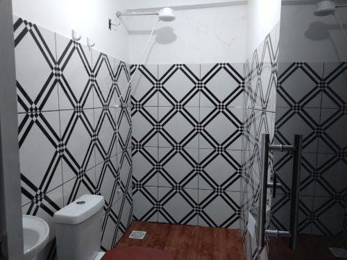 uma casa de banho com uma parede em azulejo preto e branco em Pousada Vicenzi em Luziânia