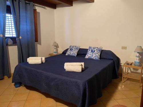 Un dormitorio con una cama azul con toallas. en La Casetta di Ninetta, en Ustica