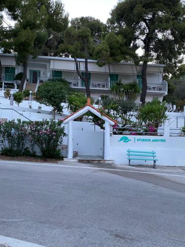 a white fence with a bench in front of a building at Studios Argyris in Poros