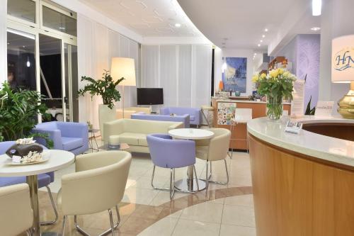 - un hall avec des chaises violettes et blanches et un comptoir dans l'établissement Hotel Meublè Nazionale, à Lignano Sabbiadoro