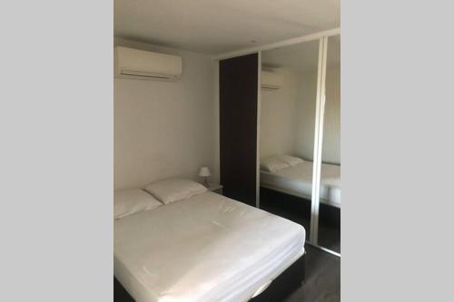 une petite chambre avec un lit et un miroir dans l'établissement La Croix-Valmer - Appartement agréable et reposant, à La Croix-Valmer