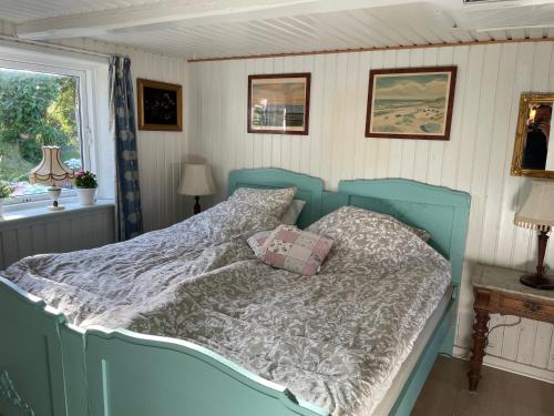 a blue bed in a room with a window at Brogaard Apartments in Løkken