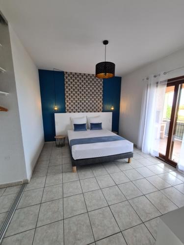 una camera da letto con letto, pareti blu e pavimenti piastrellati di Les Terrasses de Sari a Sari Solenzara