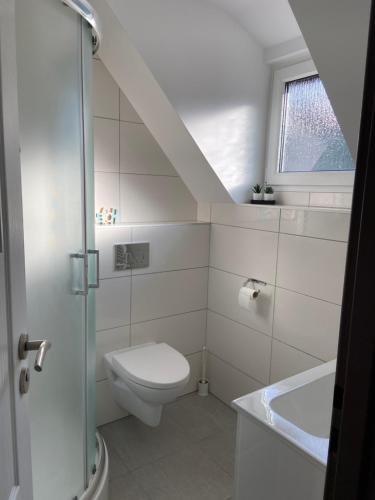 a white bathroom with a toilet and a sink at Pokoje Gościnne Kijek in Dziwnówek