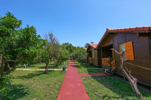 a red path next to a house with trees at Baris Pension & Bungalows in Cıralı