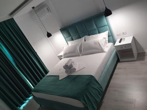 a bedroom with a large bed with a green headboard at Hotel Aloha in Sarandë