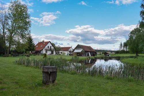 una casa en un campo con un estanque y casas en Gierszówka en Gietrzwałd