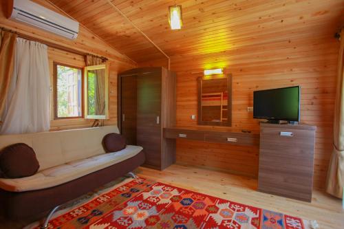a living room with a couch and a television at Baris Pension & Bungalows in Cıralı