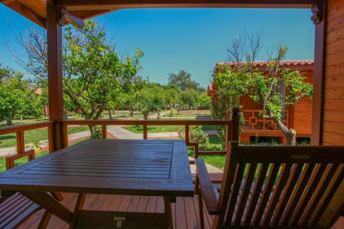 a wooden deck with a wooden table and a bench at Baris Pension & Bungalows in Cıralı