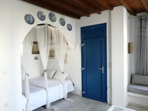 a bedroom with a blue door and white walls at Petit Andromeda Mykonos I in Mikonos