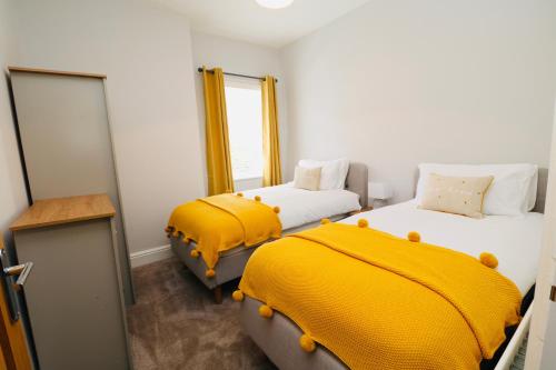 Habitación con 2 camas con sábanas amarillas y espejo. en The Hideaway - IH113AHIG en Stockton-on-Tees