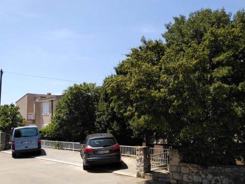 two cars parked in a parking lot next to a tree at Apartments Sabo in Kraljevica