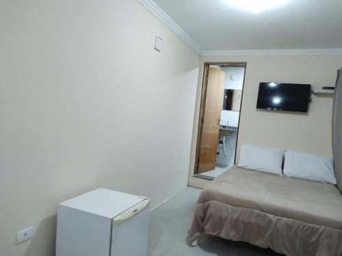 a white room with a bed and a television at Recanto Lua Clara in Campos do Jordão