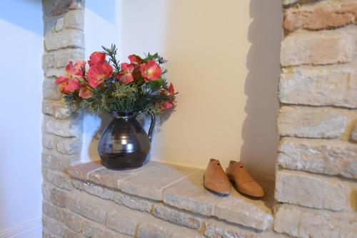 a vase of flowers sitting on a brick wall with shoes at Villa Shmitanka in Servigliano