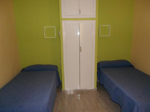 two beds in a room with green walls at Pensión Mova in Santa Cruz de Tenerife