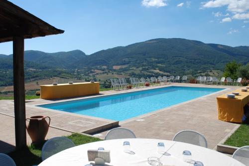 a pool with tables and chairs and mountains in the background at Il Castello Di Perchia in Crocemaroggia