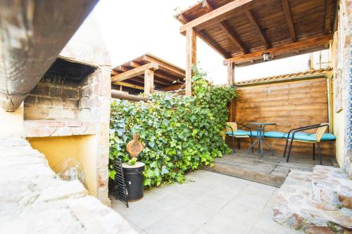 a patio with a table and chairs and a hedge at LOS SUEÑOS DE JAVIER in Robledillo