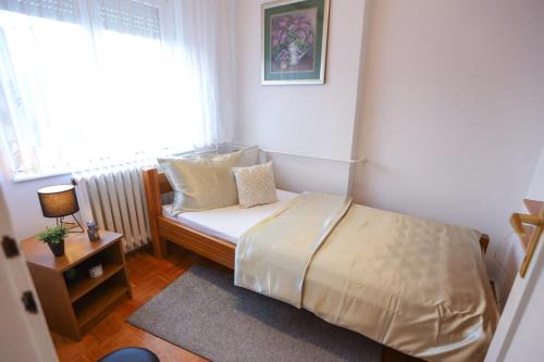 a small bedroom with a bed and a window at Apartman ZITA in Osijek