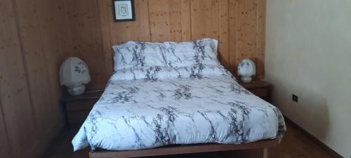 a bed with a white comforter and wooden walls at B&B La casa in Campagna in Ospedaletto