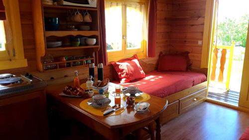 una camera con tavolo e divano in una cabina di Les Roulottes Pomponnaises a Saint-Pompont