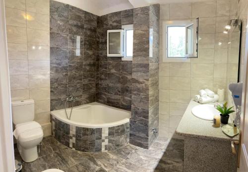 a bathroom with a tub and a toilet and a sink at Residence Poseidon in Spartia