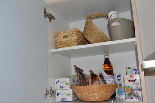 a kitchen pantry with baskets and bottles on shelves at Spacious Flat Garden&Parking 5min Basel Tram Bus Airport in Saint-Louis