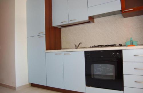 a kitchen with white cabinets and a black oven at MIMOSA CAMPING in Isca sullo Ionio