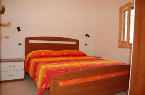 um quarto com uma cama de madeira e um edredão laranja em MIMOSA CAMPING em Isca sullo Ionio