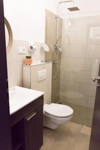 a white bathroom with a toilet and a shower at Balkon Apartmanház Panzió in Balatonfüred