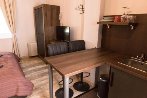 a kitchen with a table and a sink and a bed at Balkon Apartmanház Panzió in Balatonfüred