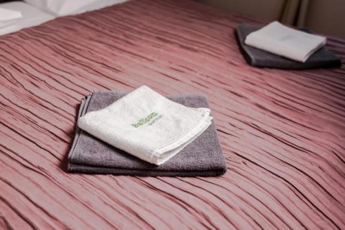 two towels are sitting on top of a bed at Balkon Apartmanház Panzió in Balatonfüred
