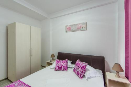 a bedroom with a bed with pink and white pillows at Apartament Nacis in Mamaia Sat/Năvodari