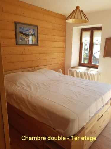une chambre avec un lit dans une pièce en bois dans l'établissement Gîte de la snaille, à Le Reposoir