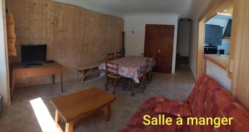 sala de estar con mesa, TV, mesa y sillas en Gîte de la snaille en Le Reposoir