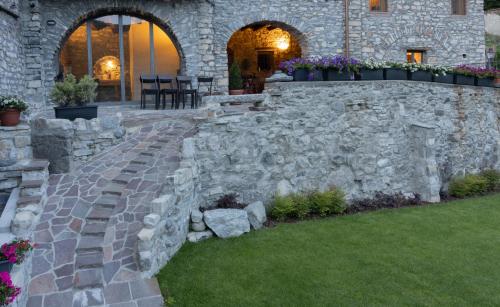 a stone retaining wall with flowers in a yard at Cà Piodèe in Faggeto Lario 