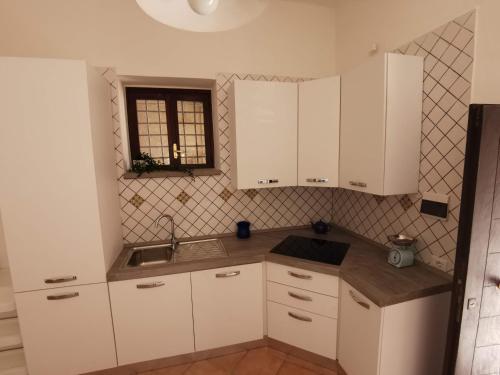 una cucina con armadi bianchi, lavandino e finestra di Casa del Porto a Scario