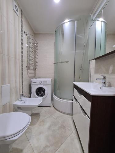een badkamer met een wastafel en een wasmachine bij 127-Avenue Apartment in Tsjernivsi