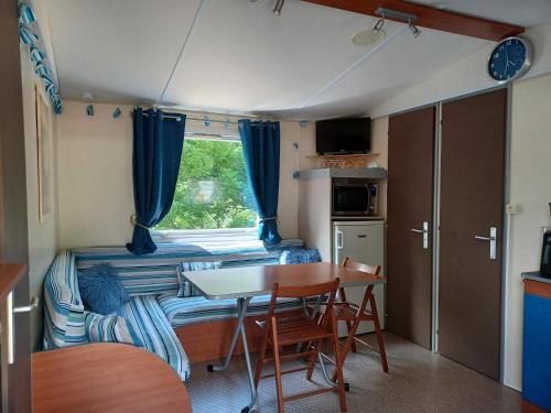 Cette caravane comprend une table, des chaises et une fenêtre. dans l'établissement Flo's Mobil-Home, à Saillagouse