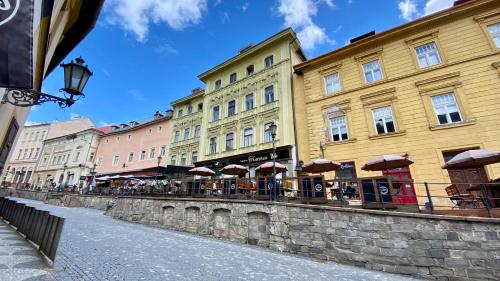 een rij gebouwen met tafels en parasols op straat bij Apartment Trotuar in Banská Štiavnica