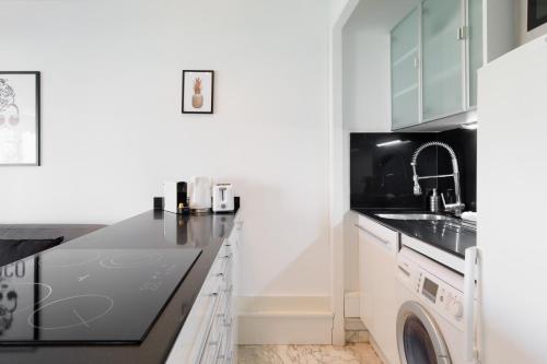 une cuisine avec des armoires blanches et une laveuse et une sécheuse dans l'établissement Phoenix YourHostHelper, à Cannes