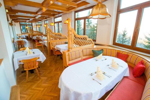 a restaurant with two tables and chairs and windows at Kurhotel Renona Rehabilitation in Semmering