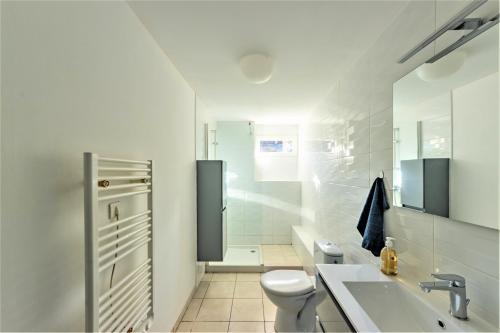 Baño blanco con aseo y lavamanos en Maison des bains - 3 chambres - Jardin - Wifi, en Valence-dʼAgen