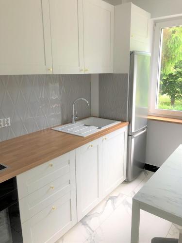 een keuken met witte kasten en een wastafel bij Sztormowa Apartment in Gdańsk
