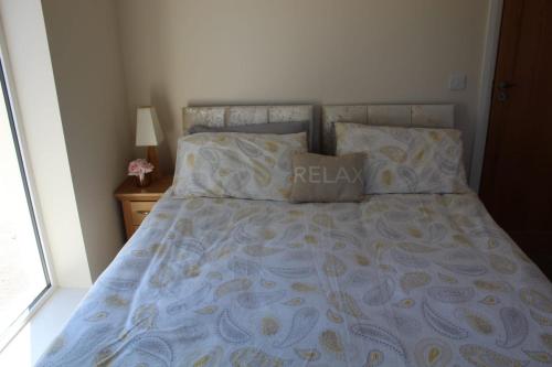 a bed with a blue and yellow bedspread and pillows at Ben Haven Self Catering Accommodation in Ballaghnatrillick