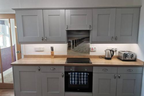 a kitchen with gray cabinets and a stove top oven at BERNARDS HIDEOUT in Cromer