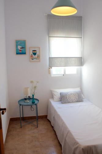 a small bedroom with a bed and a table at Casa Parpatana in Conil de la Frontera