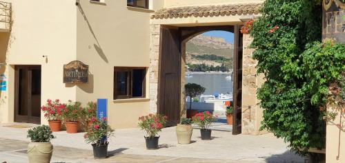 an archway with potted plants on a building with a lake at La Tonnara di Bonagia Resort in Valderice