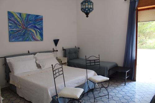 ein Schlafzimmer mit einem Bett, zwei Stühlen und einem Gemälde in der Unterkunft Villa Pedaci B&B in Santa Maria di Leuca