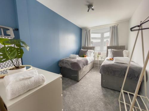 a bedroom with two beds and a blue wall at Spacious Contractor Flat for Large groups - Private Parking by Tailored Apartments in Cheshunt